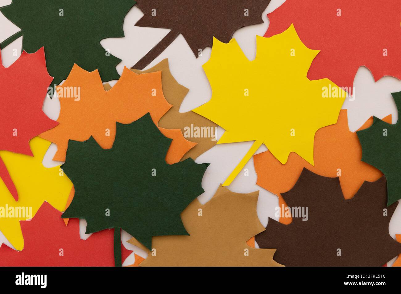 Feuilles d'automne en papier dans diverses couleurs d'automne, regroupées en gros plan sur un fond blanc, concept créatif pour les loisirs créatifs, la décoration et la saisonnalité d Banque D'Images
