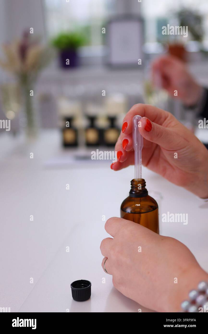 Femme utilisant un compte-gouttes en verre avec une bouteille de sérum ambré, idéal pour les soins de la peau, les cosmétiques naturels, l'aromathérapie et la publicité pour la beauté. Banque D'Images