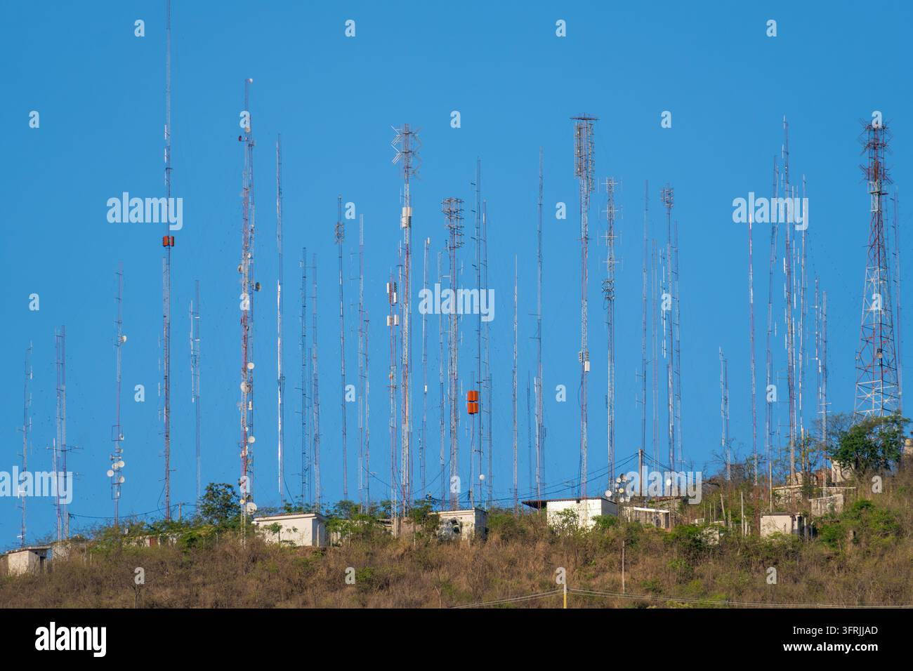 De nombreuses antennes et tours de télécommunication peuplent densément une colline, transmettant divers signaux, symbolisant la connectivité moderne et la technologie Banque D'Images