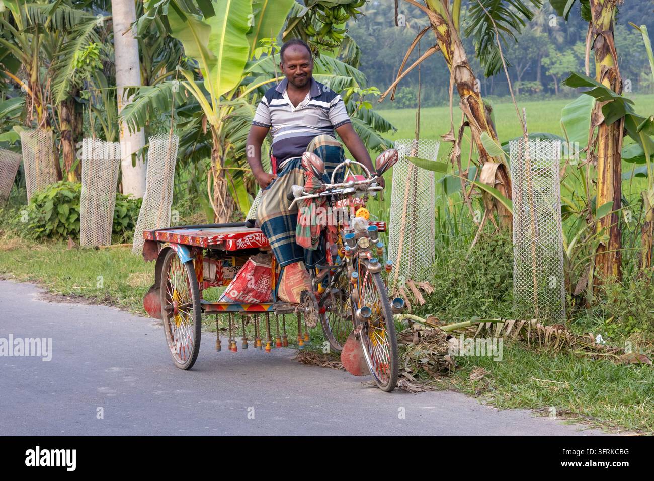 Magura, Bangladesh - 03 octobre 2026 - Conducteur rural asiatique reposant sur une van rickshaw locale traditionnelle sur une route de campagne. Style de vie des transports villageois Banque D'Images