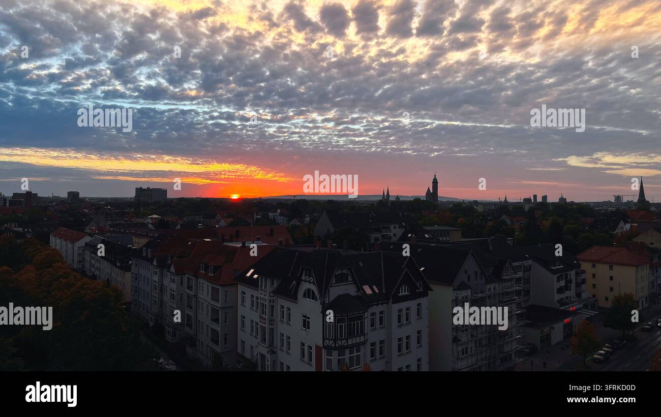Braunschweig, Basse-Saxe, Allemagne, Europe. Panorama de la ville de Braunschweig lors d'un coucher de soleil impressionnant. Le soleil bas disparaît à l'horizon tandis que des formations nuageuses dramatiques teignent le ciel de tons orange, rouges et bleus intenses. La silhouette des églises et bâtiments historiques caractérise la skyline de cette grande ville de Basse-Saxe. Image éditoriale. *** Braunschweig, Basse-Saxe, Allemagne, Europe : Une vue panoramique de la ville de Braunschweig lors d'un coucher de soleil spectaculaire. Le soleil bas disparaît derrière l'horizon tandis que des formations nuageuses dramatiques teignent le ciel de tons orange, rouges et bleus intenses. La silhouette des églises et bâtiments historiques caractérise la skyline de cette grande ville de Basse-Saxe. Image éditoriale. Banque D'Images