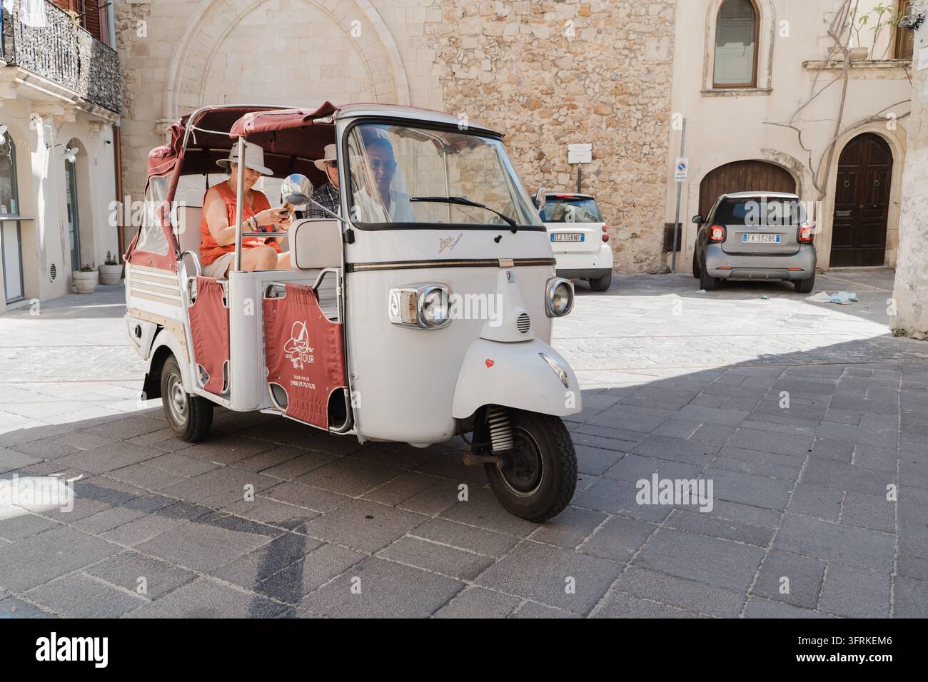 Couple en visite en tuk-tuk dans un village historique italien Banque D'Images