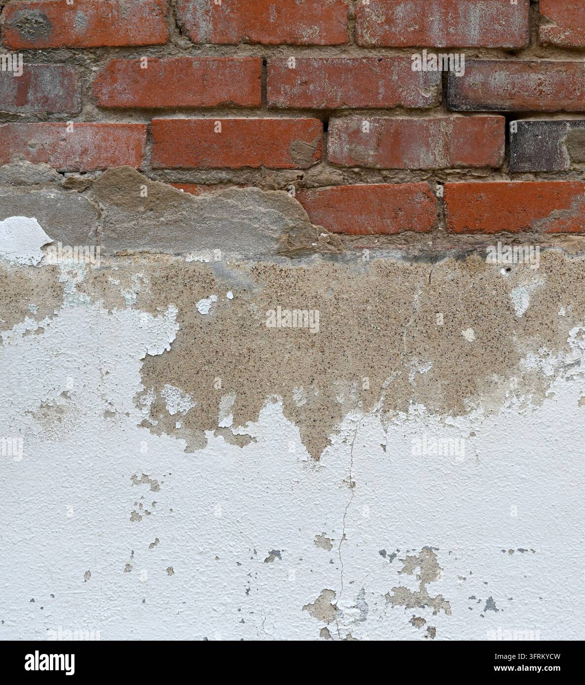 Brique d'argile rouge patinée et mur en béton peint en blanc avec brique supérieure exposée, béton fissuré et écaillant, agrégat visible, bords ébréchés Banque D'Images