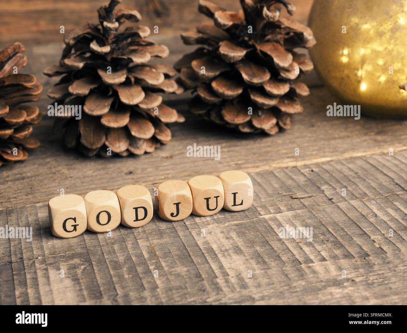 Petit bloc de bois avec les mots God Jul et des pommes de pin sur un fond en bois, Joyeux Noël scandinave Banque D'Images