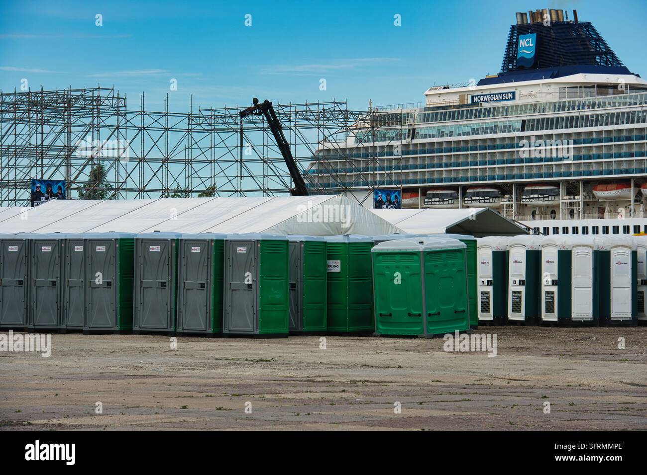 Toilettes mobiles alignées près de l'échafaudage de la scène et du navire de croisière Banque D'Images