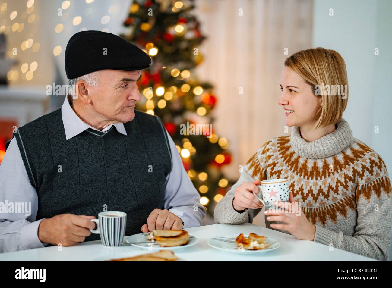 Grand-père et fille partageant une conversation pendant le petit-déjeuner de Noël Banque D'Images
