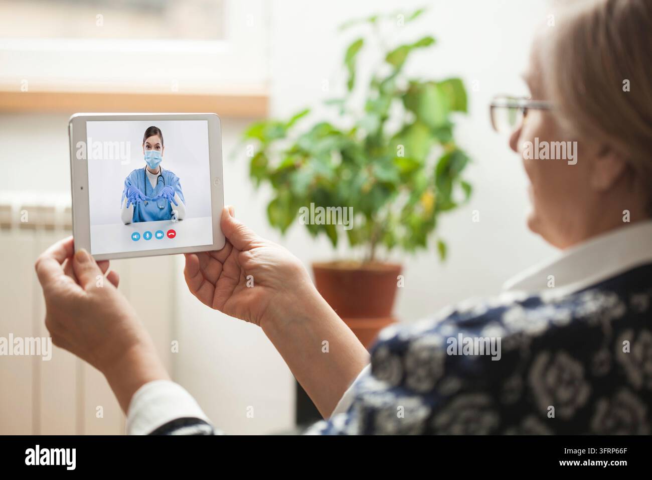 Consultation e-doctor pour une femme senior, ancienne pensionnée assise à la maison, appel vidéo numérique en ligne via une tablette avec l'application on-mean help, fournissant su Banque D'Images