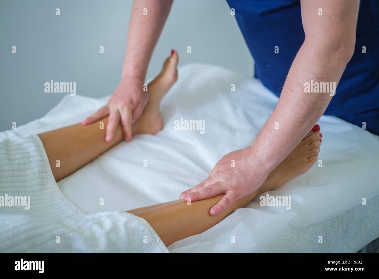 Dans un salon de beauté, ce service professionnel propose un massage des jambes, un massothérapeute, une femme, un massage du mollet, un massage thérapeutique et des mains duri Banque D'Images