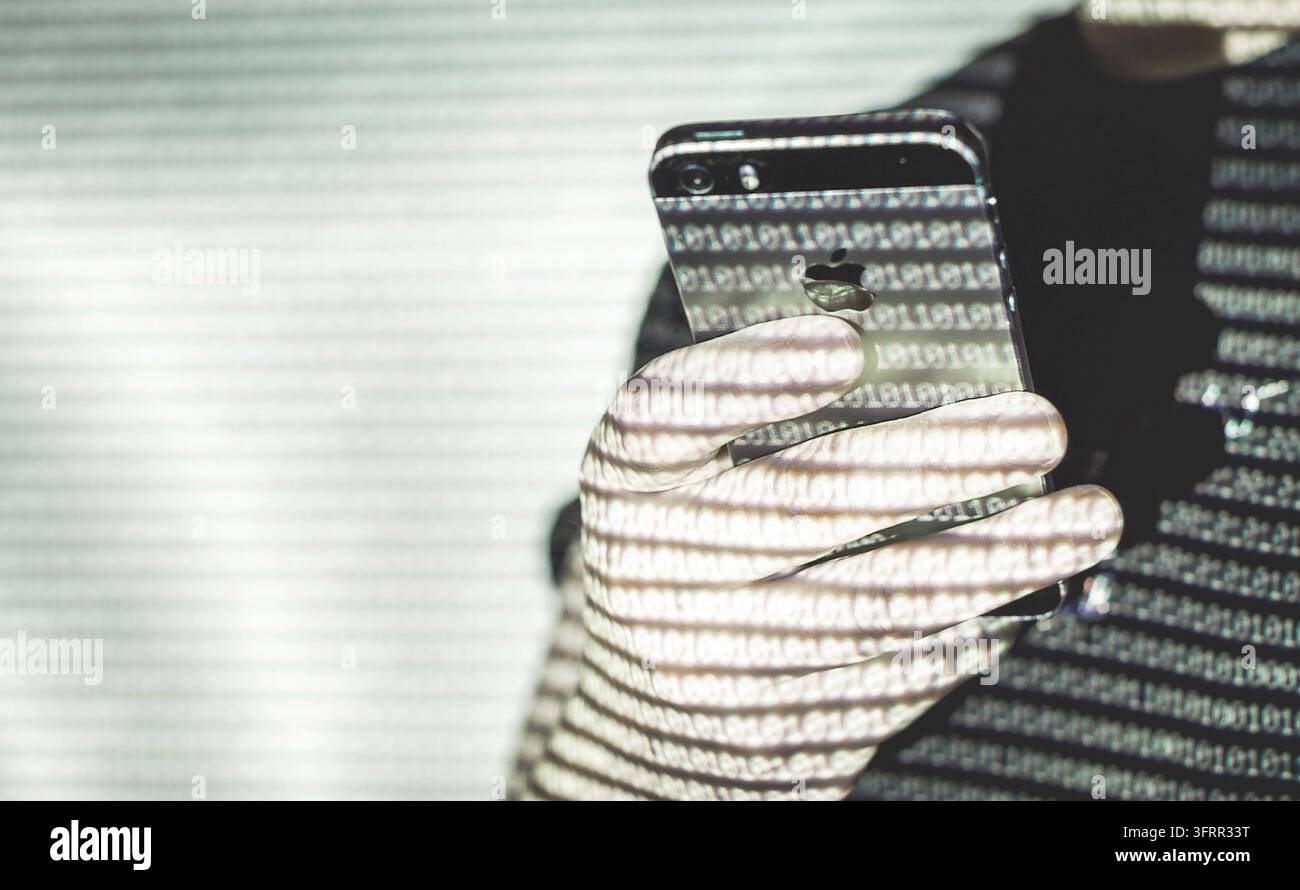 Vienne Autriche 10 décembre 2019, Jeune homme tenant Apple iPhone se tout en étant illuminé avec des codes binaires Banque D'Images