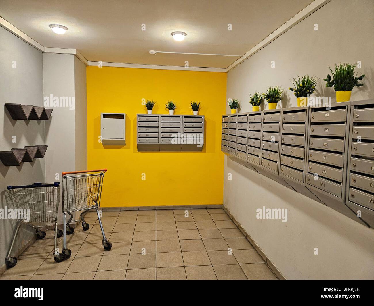 La pièce est jaune et comporte un chariot et des plantes en pot, des boîtes aux lettres dans l'entrée de la maison Banque D'Images