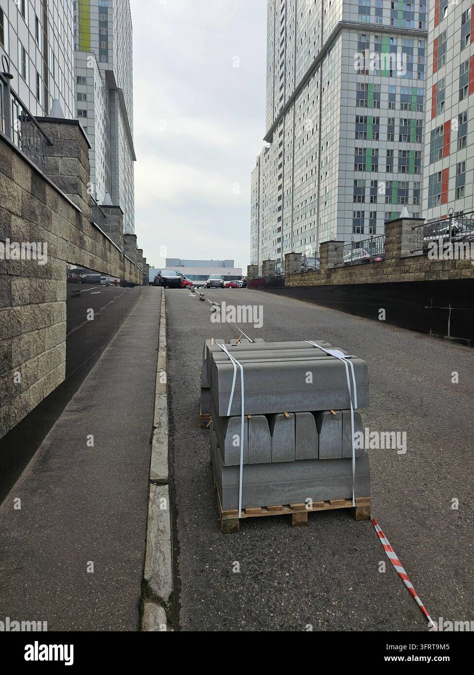 Un tas de briques de bordure se trouve dans la rue devant un bâtiment. Les briques sont attachées ensemble avec une corde Banque D'Images