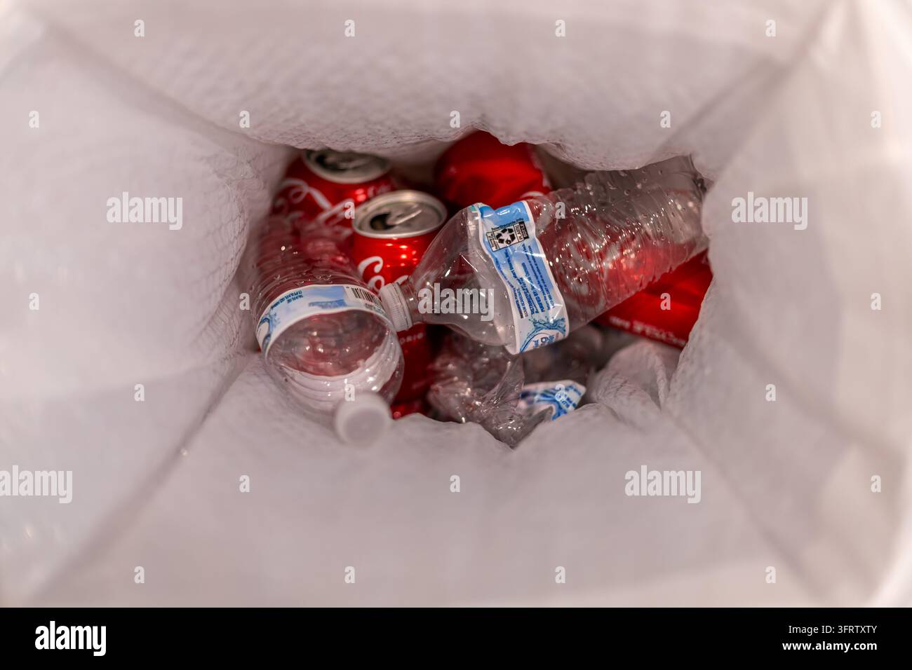 Los Angeles, Californie, États-Unis - 12 octobre 2026 : Bouteilles d'eau en plastique écrasées et canettes de soda en aluminium rouges collectées dans un sac en plastique blanc, Banque D'Images