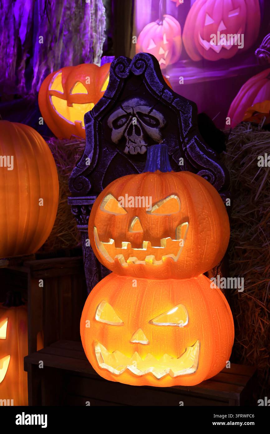 Décorations d'Halloween effrayantes avec des citrouilles Jack O'Lantern lumineuses et une pierre tombale inquiétante Banque D'Images