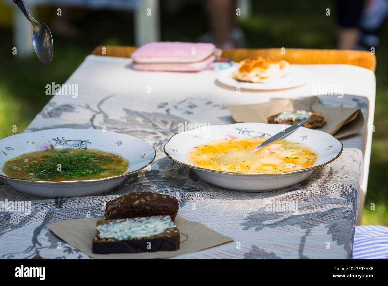 Soupe de poisson traditionnelle servie dans des bols en porcelaine décoratifs à une table de plein air, accompagnée d'aneth frais, de pain de seigle noir avec une tartinade aux herbes. Banque D'Images