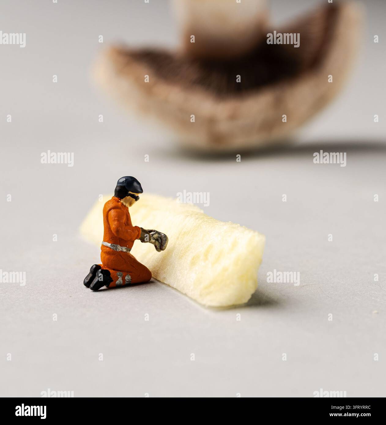 Travailleurs miniatures collaborant sur des courgettes fraîches sur un fond gris clair Banque D'Images