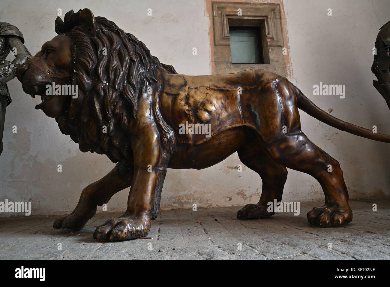 Vue de profil en pleine longueur d'une majestueuse statue de lion en bronze à l'intérieur d'un couloir d'un château historique de prince. Banque D'Images
