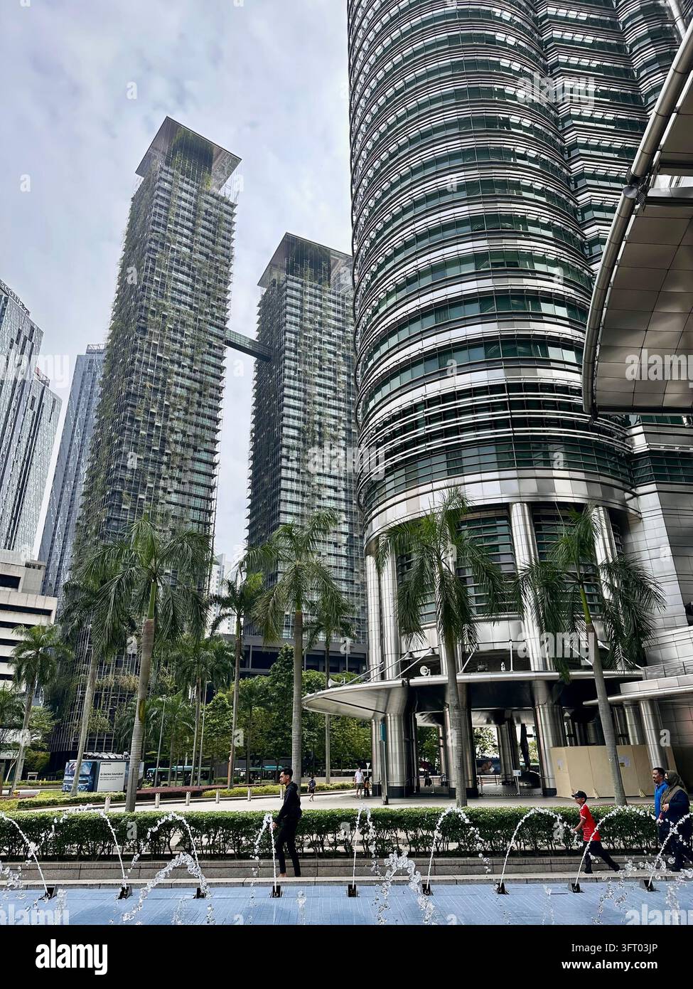 Kuala Lumpur, Malaisie – 27 novembre 2022 : skyline urbaine, arbres urbains, immeubles de grande hauteur, canopée verte, route urbaine, façades en verre, ciel bleu, nuages - Image de stock capturée avec un smartphone