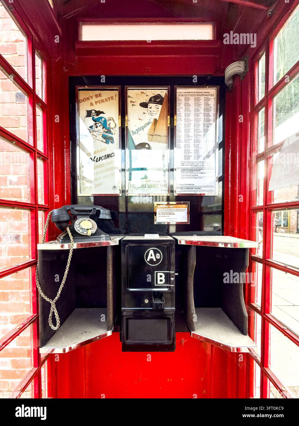 Intérieur d'un kiosque téléphonique rouge traditionnel K6 avec combiné en bakélite, fente à pièces et affiches - Image de stock capturée avec un smartphone