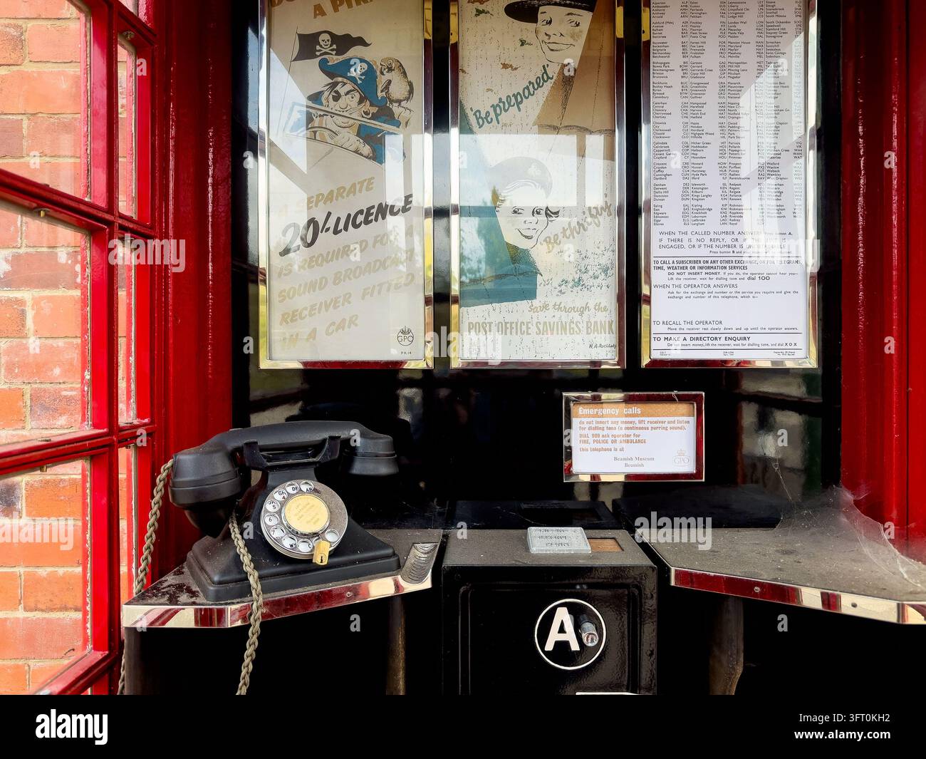 Intérieur d'un kiosque téléphonique rouge traditionnel K6 avec combiné en bakélite, fente à pièces et affiches - Image de stock capturée avec un smartphone