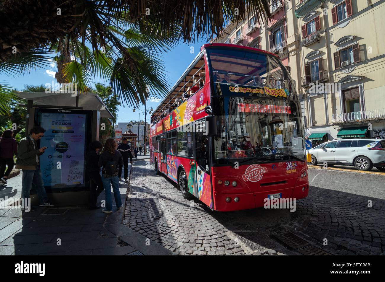 Le bus touristique CitySightSeeing passe devant un abribus à une arrêt de bus sur la Piazza Dante, Naples, Italie. Banque D'Images