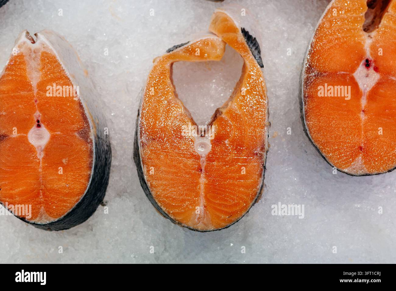 Steaks de saumon congelés et poisson rouge cru présentés sur glace pour la vente au détail de fruits de mer au marché du poisson, offrant des ingrédients riches en protéines nutritives pour des repas sains et la cuisine maison. Banque D'Images
