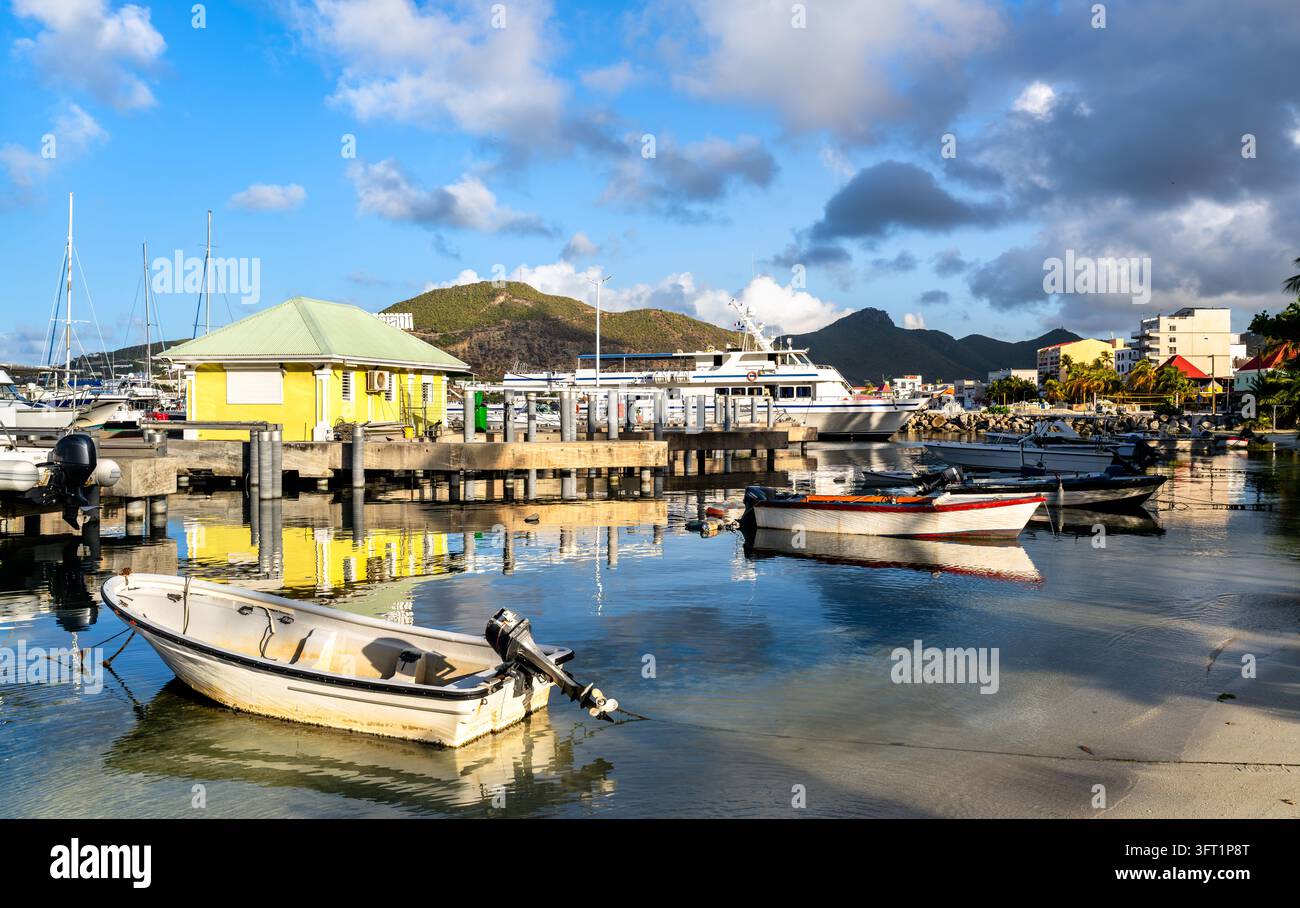 Petits bateaux amarrés dans des eaux calmes près d'une jetée et de Bobby's Marina avec des collines verdoyantes à Philipsburg, Sint Maarten, Pays-Bas caribéens Banque D'Images