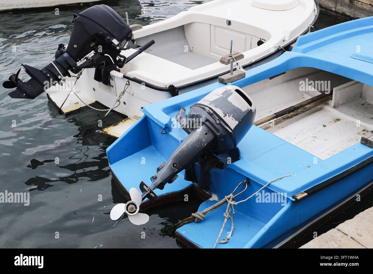 Petits bateaux à moteur avec moteurs hors-bord amarrés côte à côte dans la marina. Arrière-plan de transport aquatique pour les bateaux de loisirs, l'équipement marin et la pêche Banque D'Images