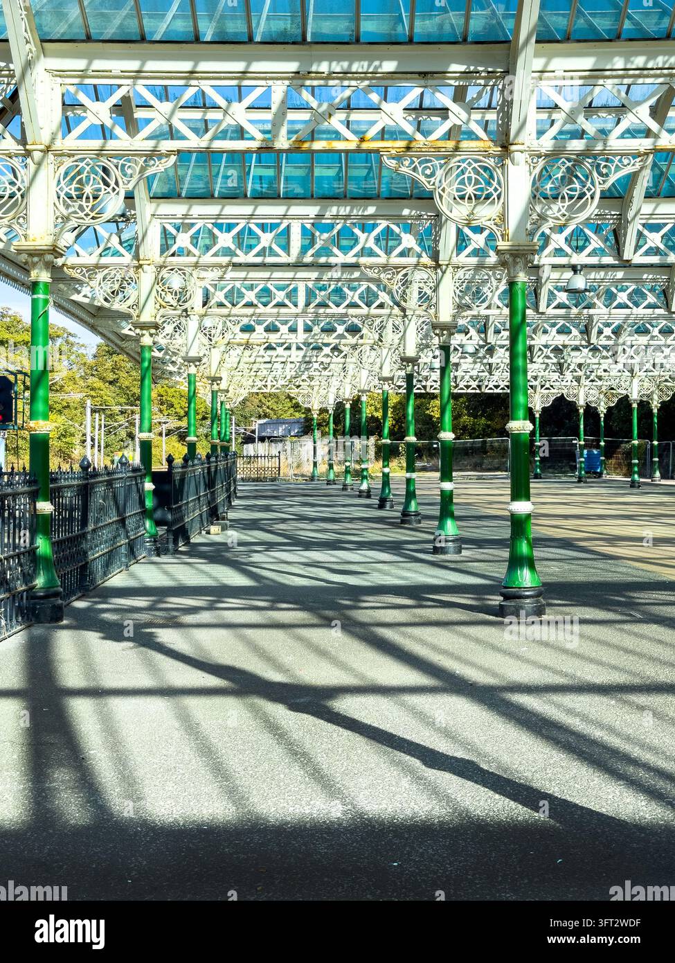 Canopée de quai victorien avec des colonnes de support vertes et des ferronneries projetant des ombres sur le sol à la gare de métro de Tynemouth Banque D'Images