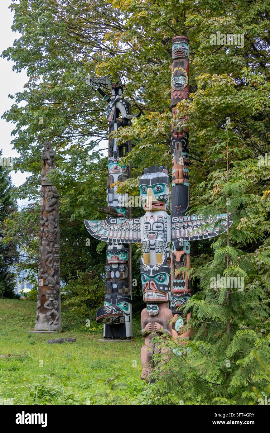 Vancouver, Canada - 7 septembre 2026 : Composition à hauteur des yeux verticale montrant des poteaux totémiques en cèdre indigènes authentiques sculptés et peints entourés de Banque D'Images