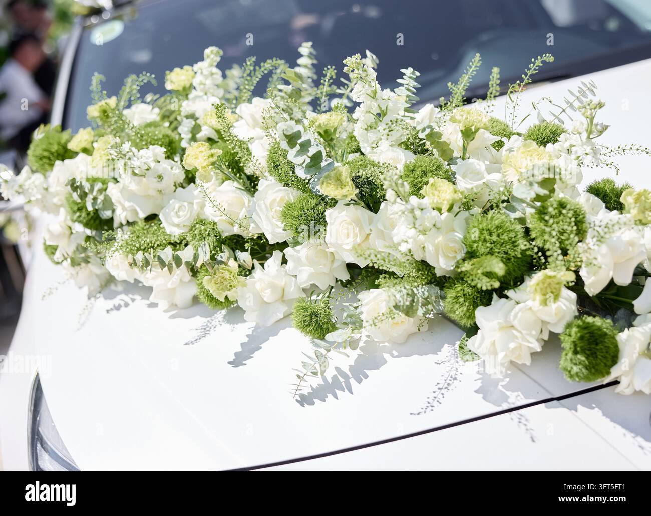 Guirlande florale blanche luxueuse décorant le capot d'une voiture de mariage blanche pour la mariée Banque D'Images