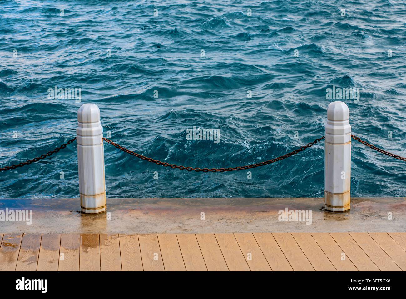 Boulards d'amarrage blancs avec une chaîne sur un quai riverain Banque D'Images