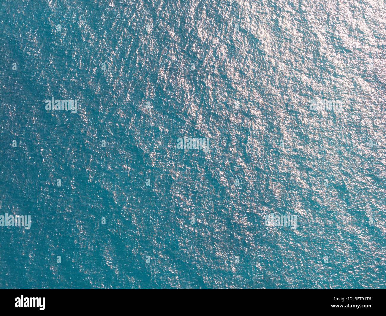 Vue aérienne de la surface de la mer turquoise avec la lumière du soleil scintillante se reflétant sur l'eau à Manggis, Bali, Indonésie. Banque D'Images