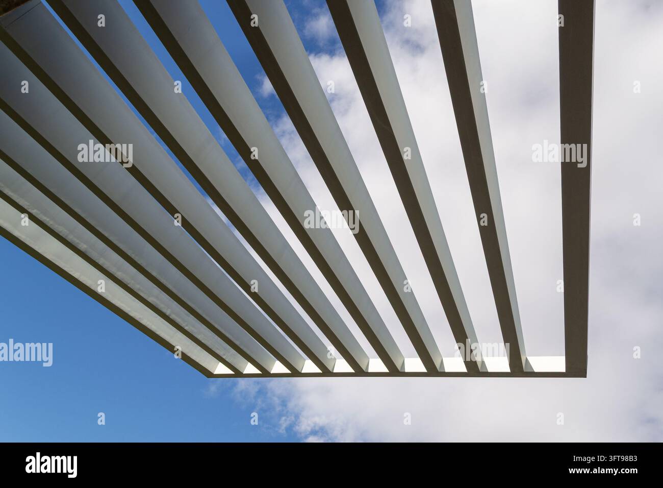 Poutres architecturales diagonales contre un ciel bleu et des nuages Banque D'Images
