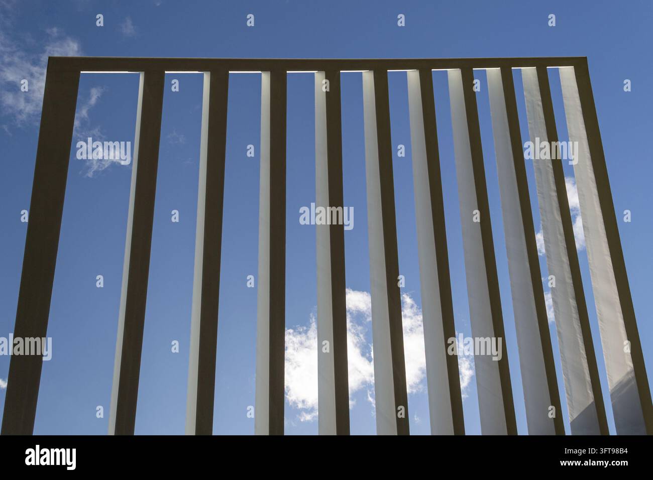 Lames architecturales parallèles encadrant un ciel bleu et des nuages blancs Banque D'Images