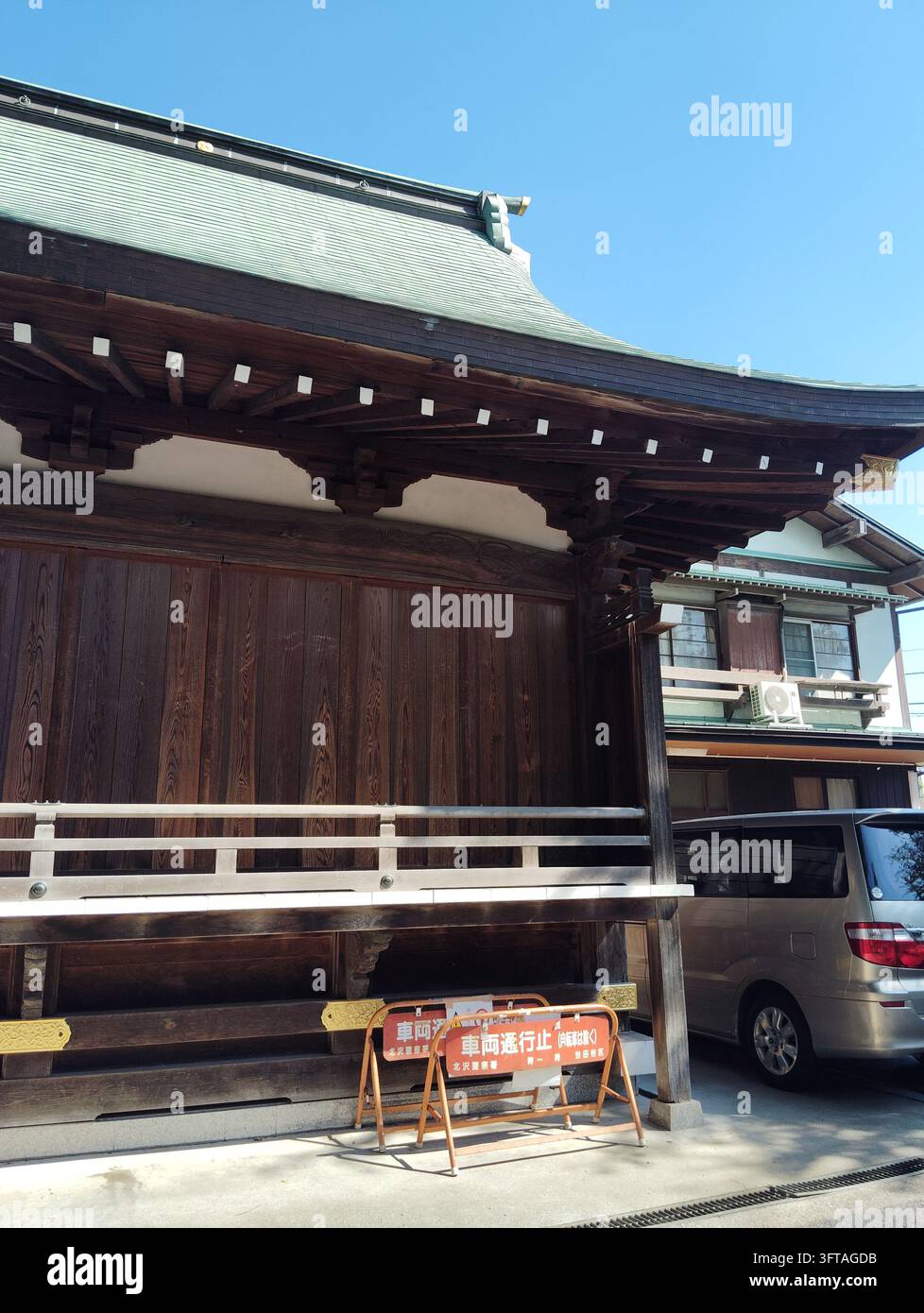 Bâtiment traditionnel de sanctuaire en bois avec toit en tuiles et barrières de restriction de véhicules à Setagaya, Tokyo, Japon. - Image de stock capturée avec un smartphone
