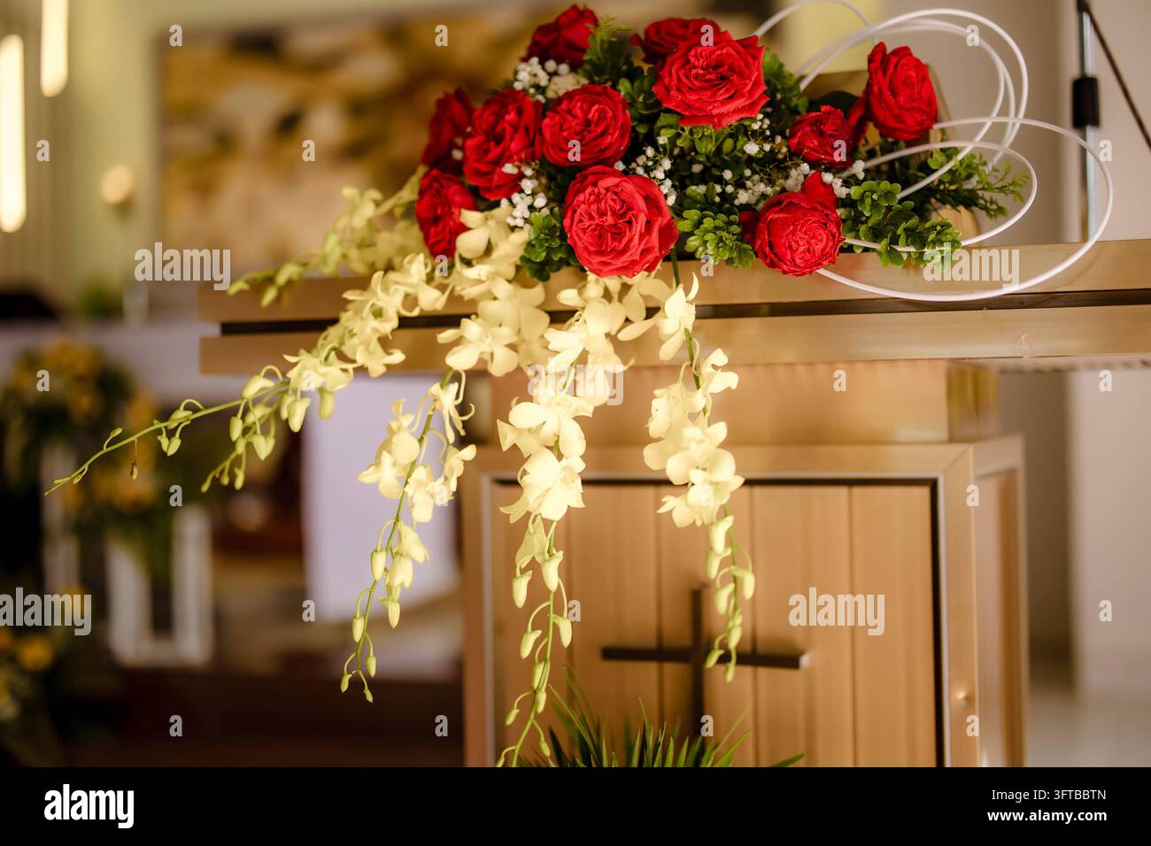 Arrangement floral de roses rouges et orchidées blanches sur le chœur d'une église Banque D'Images