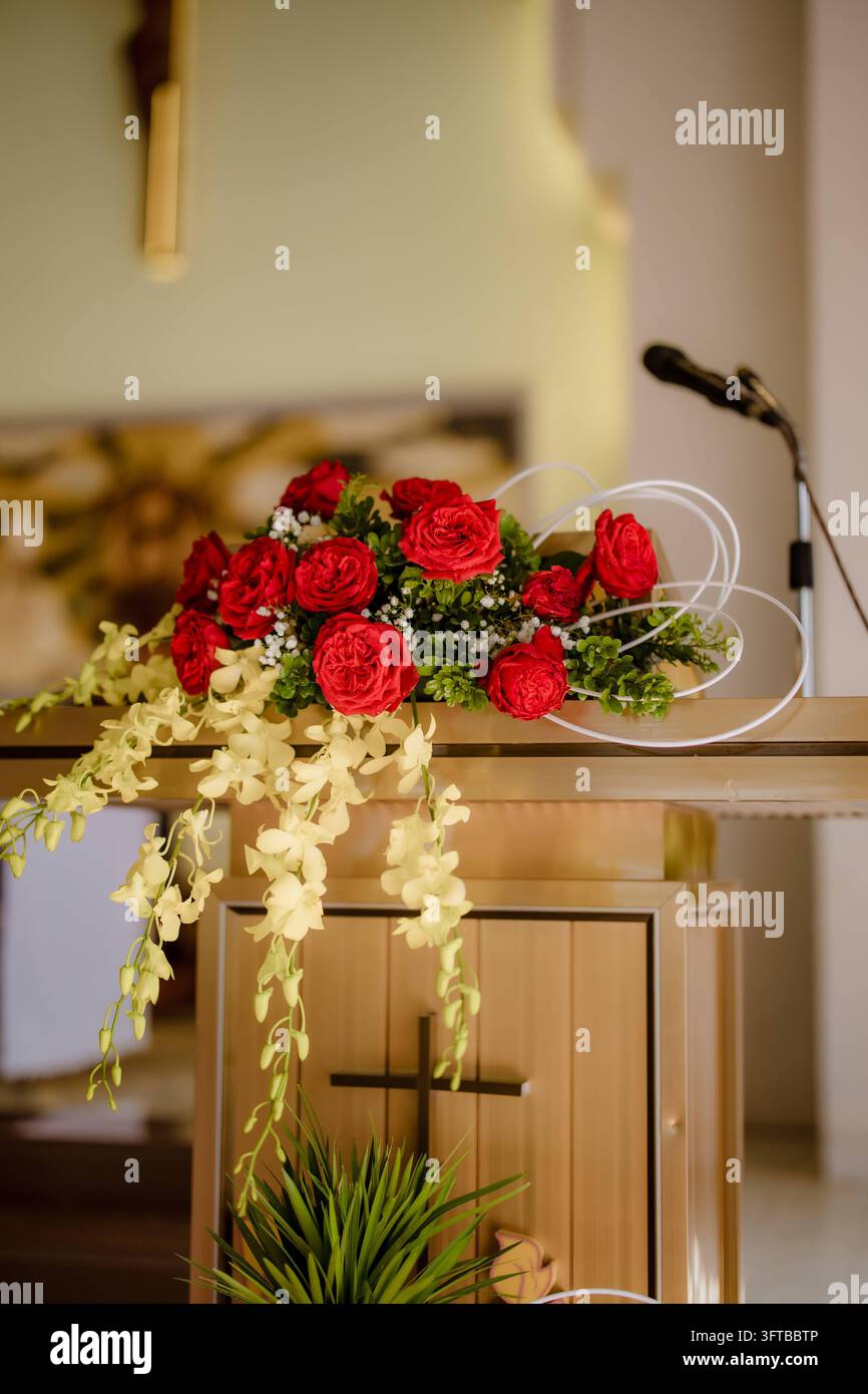 Arrangement floral de roses rouges et orchidées blanches sur le chœur d'une église Banque D'Images