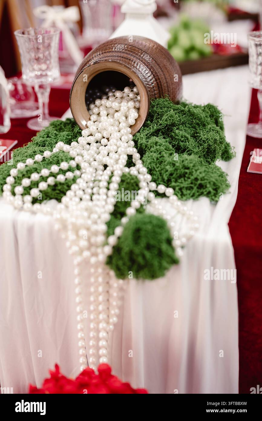Pot en argile renversant des perles blanches sur un centre de table en mousse verte sur la table de mariage Banque D'Images