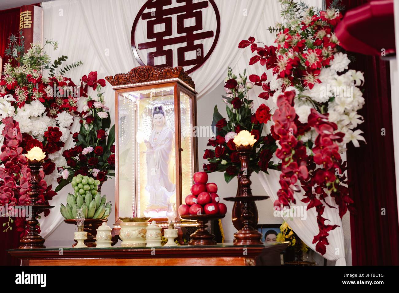 Autel traditionnel de Guan Yin décoré du symbole du double bonheur et de fleurs fraîches Banque D'Images
