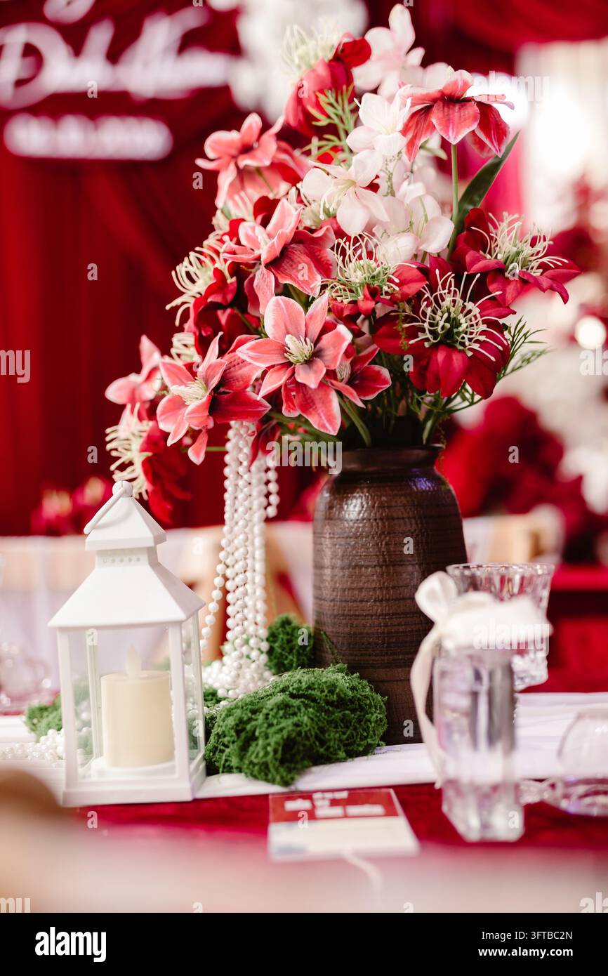 Centre de table floral rose et rouge avec lanterne blanche et perles Banque D'Images