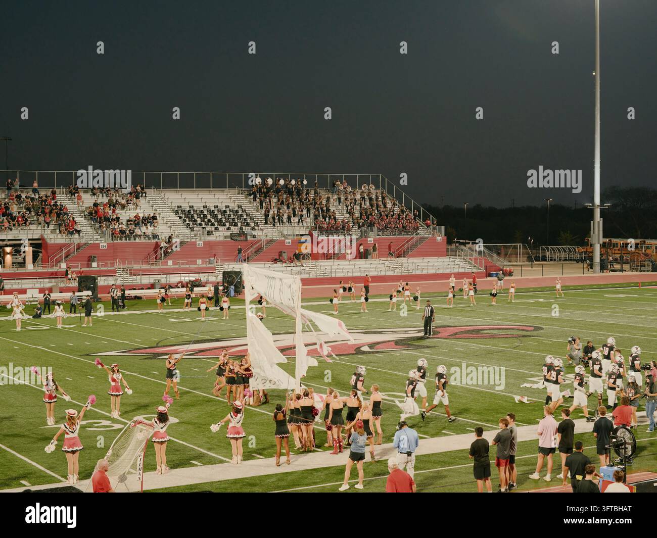 Cheerleaders et garde des couleurs avec des drapeaux blancs sur un terrain de football Banque D'Images