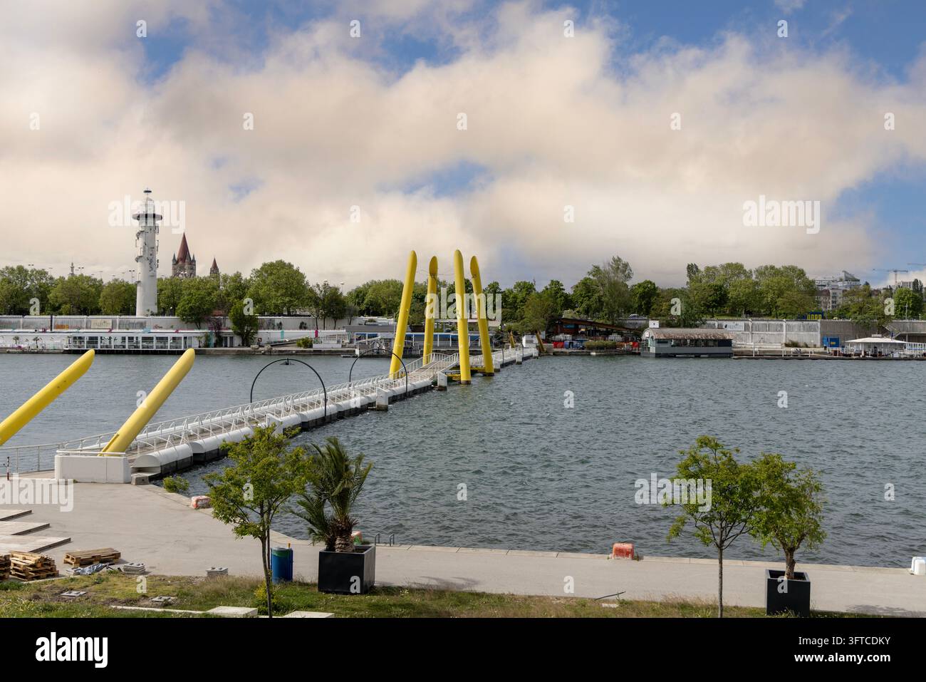 Vienne, Autriche - 25 avril 2024 : Le pont flottant Ponte Cagrana avec ses pylônes jaunes distinctifs au-dessus de la Nouvelle Danube. Vue panoramique de la plage de Copa Banque D'Images