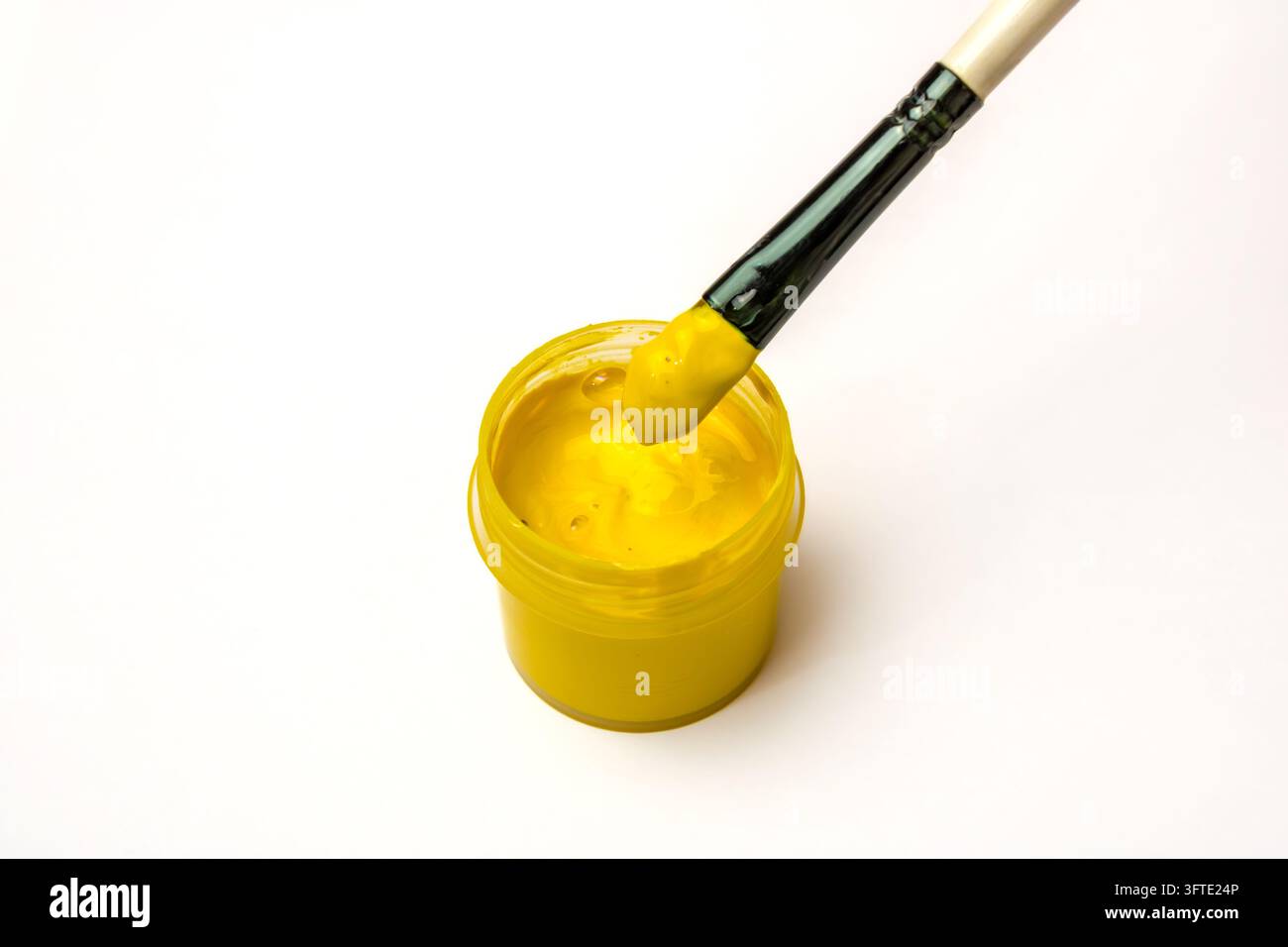 Peinture jaune sur un pinceau à côté d'une boîte de peinture à l' gouache Banque D'Images