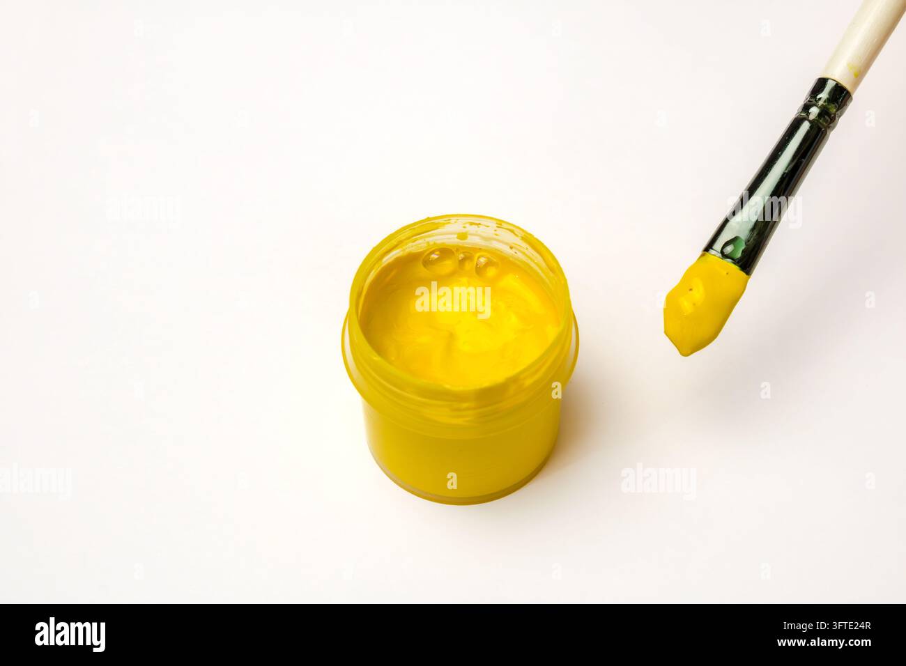 Peinture jaune sur un pinceau à côté d'une boîte de peinture à l' gouache Banque D'Images