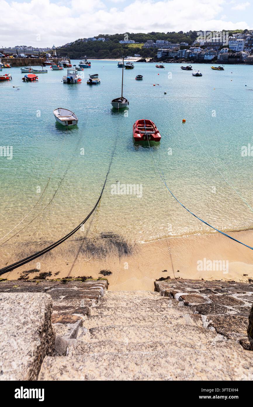 St Ives, Cornouailles, Royaume-Uni. Bateaux de pêche traditionnels et bateaux de loisirs amarrés dans les eaux calmes du port de St Ives avec la digue du port, phare Banque D'Images
