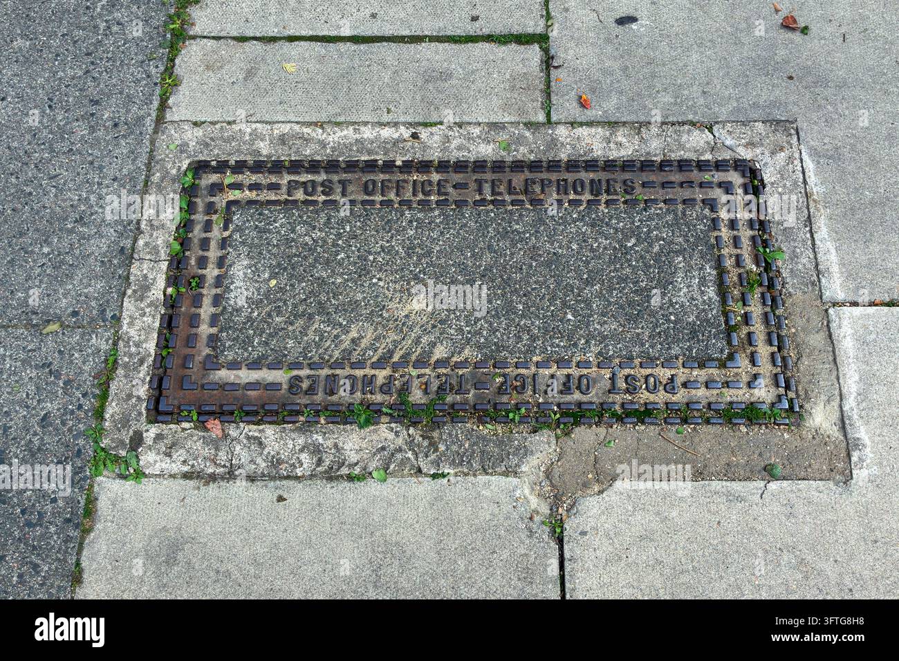 Un couvercle d'inspection vintage des téléphones du Post Office fait d'un cadre en fonte avec un remplissage en béton dans une rue résidentielle, Nord-Londres, Royaume-Uni Banque D'Images