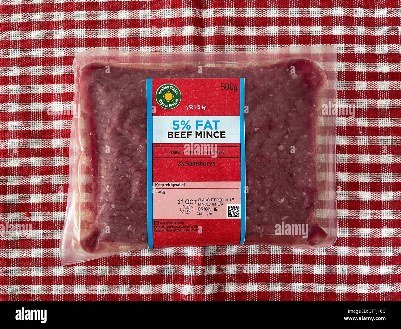 Un paquet scellé de haché de bœuf irlandais 5 % de Sainsbury's sur une nappe à carreaux rouges - Image de stock capturée avec un smartphone