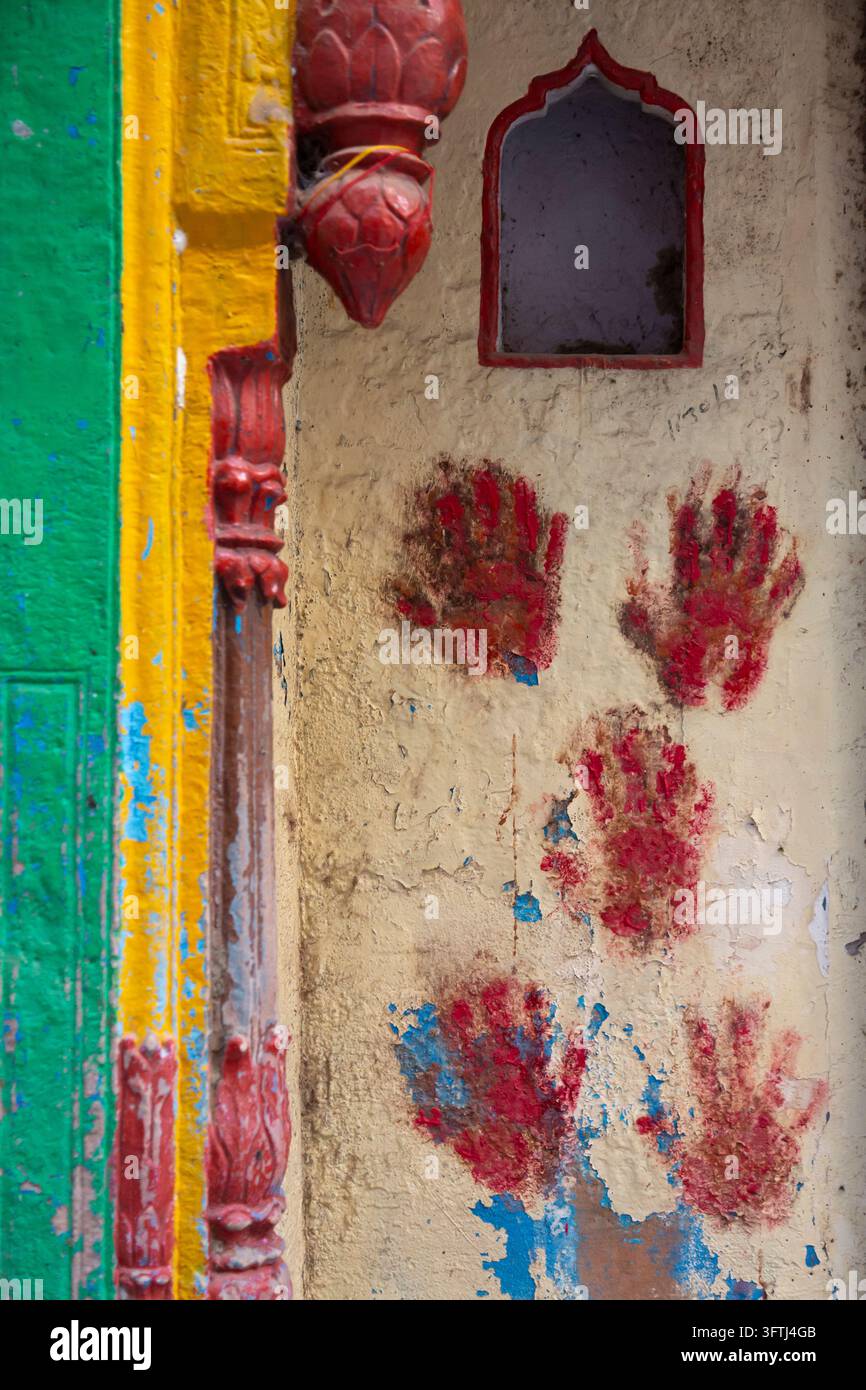 Close up d'empreintes de poudre rouge pressées sur un mur couleur crème écaillant, Uttar Pradesh, Gokul, Inde Banque D'Images