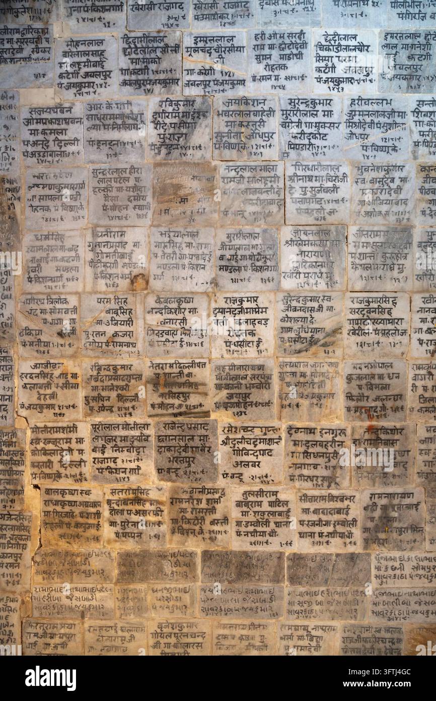 Détail d'un mur de temple recouvert de rangées de tuiles de marbre gravées des noms de donateurs et de dévots en hindi, Uttar Pradesh, Gokul, Inde Banque D'Images