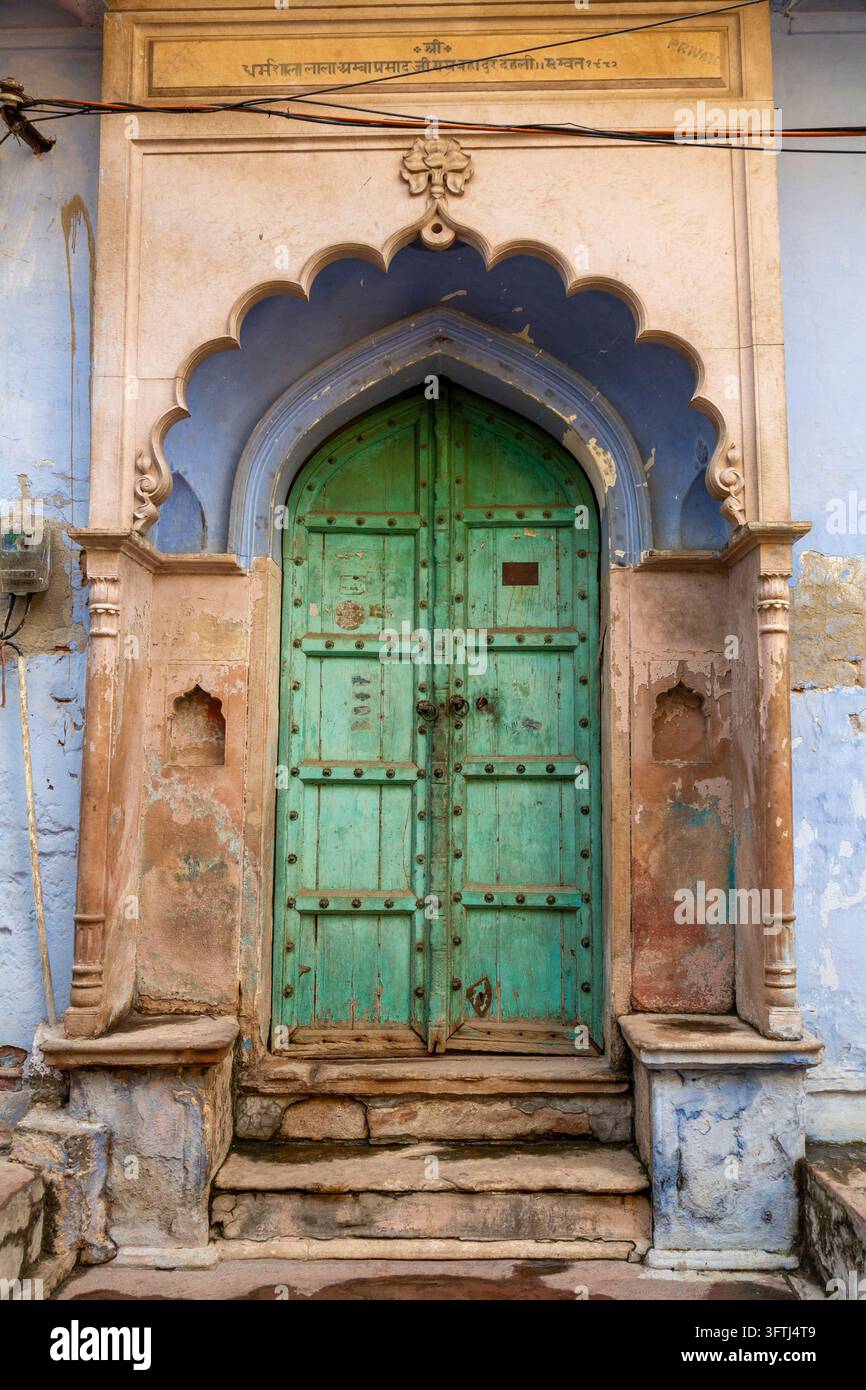 Double porte en bois vert cloutée sous une arche bleue festonnée avec une inscription, Uttar Pradesh, Vrindavan, Inde Banque D'Images